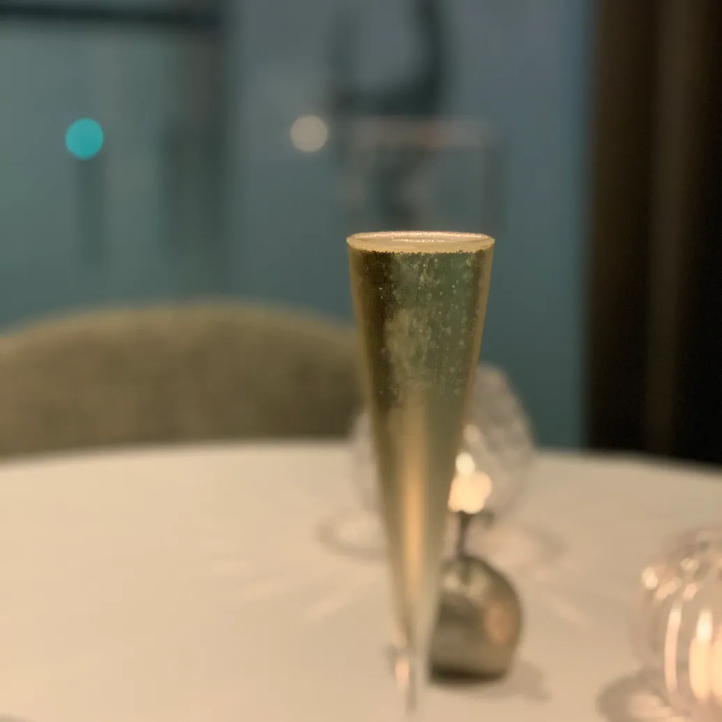 Un verre à champagne partiellement rempli posé sur une table blanche avec un fond flou